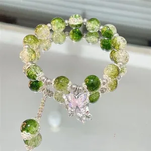 Detailed shot of a green crackle bead bracelet featuring a crystal butterfly charm