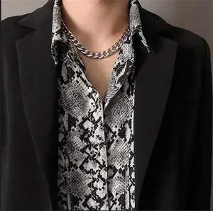 Vue détaillée d'un collier à mailles cubaines en acier inoxydable argenté porté avec un blazer noir.