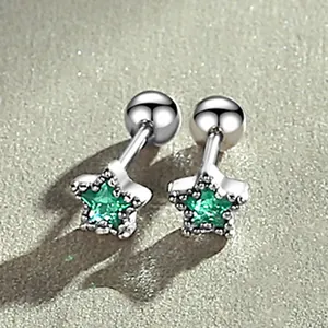 Close-up of silver-tone star stud earrings featuring vibrant green crystal gemstones