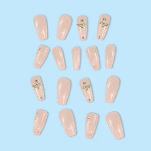 Nude pink press-on nails with golden butterfly and star patterns for a gentle look
