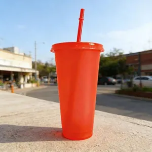 Detail view of a 24oz orange glitter straw cup in outdoor natural sunlight.