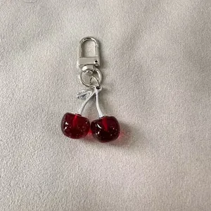 Detailed macro shot of a glittery red cherry keychain with a silver metallic clasp.
