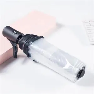 Macro view of a compact transparent automatic folding umbrella featuring a sleek black handle