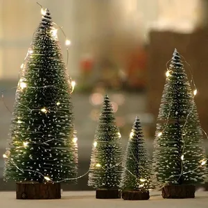 Miniature snowy Christmas trees with warm LED string lights for festive desktop decorations.