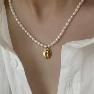 Detailed view of an elegant freshwater pearl necklace with a gold flower pendant.