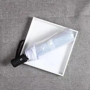 Close-up of a folded transparent umbrella with a black handle on a white tray.