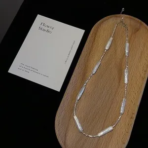 Close-up of handmade baroque pearl necklace displayed on a wooden tray background.
