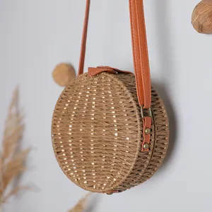 Vue détaillée d'un sac à bandoulière rond en paille tissée vintage avec une lanière en cuir orange