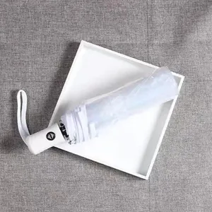Portable white folding transparent umbrella with automatic handle shown on a white tray