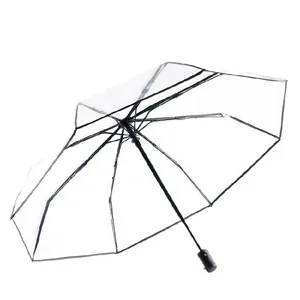 Clear transparent folding umbrella with black frame and handle on white background
