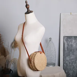 Sac à bandoulière rond en paille tressée sur un mannequin pour voir la taille.
