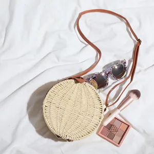 Vue de dessus d'un sac bandoulière rond en paille tissée avec accessoires d'été