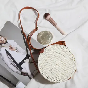 Sac à bandoulière rond en paille bohème présenté avec accessoires lifestyle