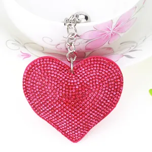 Close-up of a fuchsia heart-shaped keychain fully covered in sparkly rhinestones.