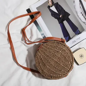 Vue de dessus d'un sac à bandoulière rond en paille tissée avec une lanière en cuir marron