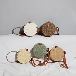 Sélection de sacs à bandoulière ronds en paille tissée en cinq tons terreux pour la plage.