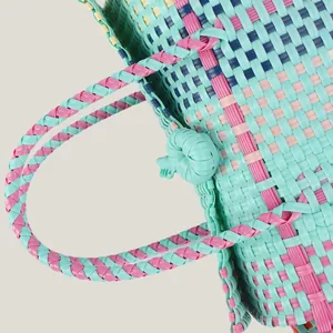 Detailed view of colorful hand-woven plastic basket bag with contrast patterns for beach picnic