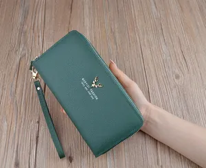 Dettaglio di un portafoglio lungo in pelle martellata verde con logo a cervo