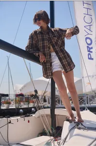 Lifestyle view of a vintage plaid shirt worn on a yacht against a sunny blue sky