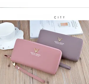 Close-up of stylish double zipper long wallets with deer ornament on wood