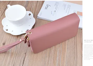 Close-up of a dusty pink double-zipper long leather clutch wallet on a desk