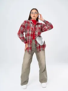 Woman wearing a vintage red plaid mid-length shirt with pockets and silver heart bag