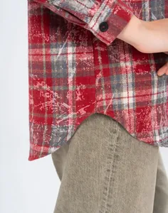 Detail of vintage red plaid flannel shirt showing distressed fabric and curved hem