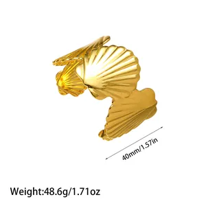 Detailed macro view of a golden shell-shaped stainless steel cuff bracelet showing size