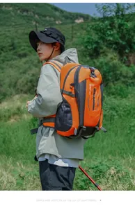 Orange 40L waterproof hiking backpack worn by a traveler in an outdoor mountain setting