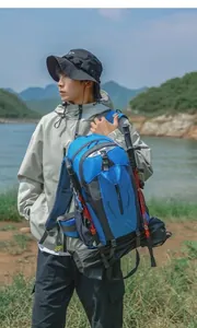 Model carrying a blue 40L outdoor hiking backpack in a scenic lakeside setting.