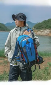 Model carrying a blue 40L outdoor hiking backpack in a scenic lakeside setting.