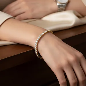 Close-up detail of a sparkling gold-tone cubic zirconia tennis bracelet on a wrist.