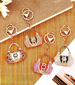 Macro detail view of four colorful rhinestone handbag keychains on a textured bamboo mat background