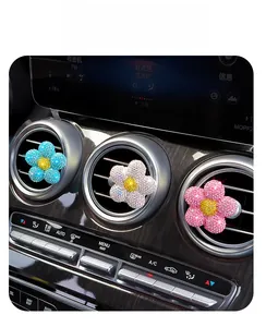 Nahaufnahme von funkelnden Strassblumen-Aromatherapie-Clips an Autolüftungsschlitzen