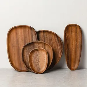 Set of four natural acacia wood serving trays in various geometric shapes for food.