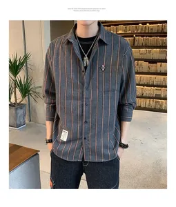 Detail of a men's loose-fit long-sleeved shirt with orange vertical stripes on grey.