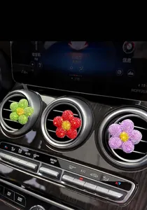 Glitzernde Blumen-Autolüftungsclips in Grün, Rot und Lila am Armaturenbrett montiert.