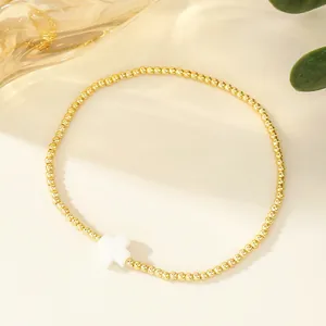 Vista dettagliata di un bracciale di perline dorate vintage con pendente a croce bianca