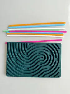 Top-down detail of dark teal silicone sensory activity board and colorful sticks