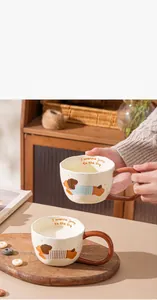 Close-up of a hand holding a creative cartoon puppy ceramic mug with a wavy rim