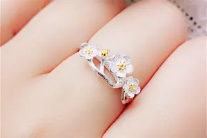 Close-up of elegant silver and gold floral open ring with delicate petal details on finger