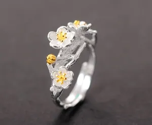 Detailed macro view of a silver cherry blossom branch open ring with golden stamen