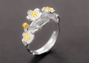 Close-up macro detail of a silver floral branch ring with delicate golden flower accents.