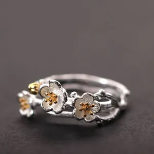 Close-up view of a silver branch-style ring with frosted white flowers and gold centers