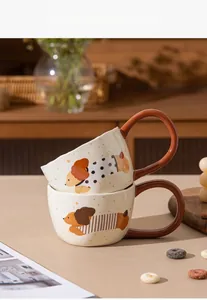 Close-up view of two stacked cream ceramic mugs featuring cute cartoon dog patterns