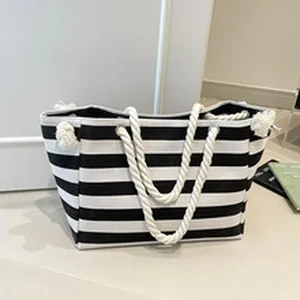 Front view detail of a black and white striped canvas tote bag with rope handles