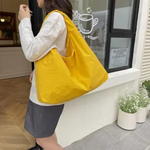 Large yellow ethnic style shoulder bag for women worn by a model in a street setting