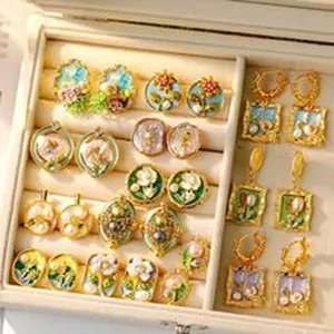 Collection of vintage-style floral and pearl earrings displayed in a soft velvet jewelry box