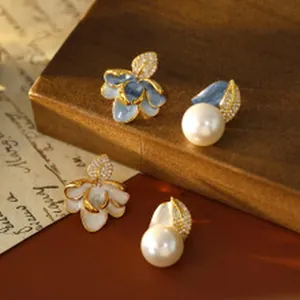Detail view of elegant floral and pearl earrings with cubic zirconia leaves on wooden background
