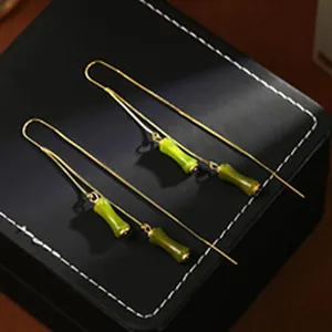 Detailed macro shot of elegant gold-toned drop earrings featuring green bamboo-joint beads